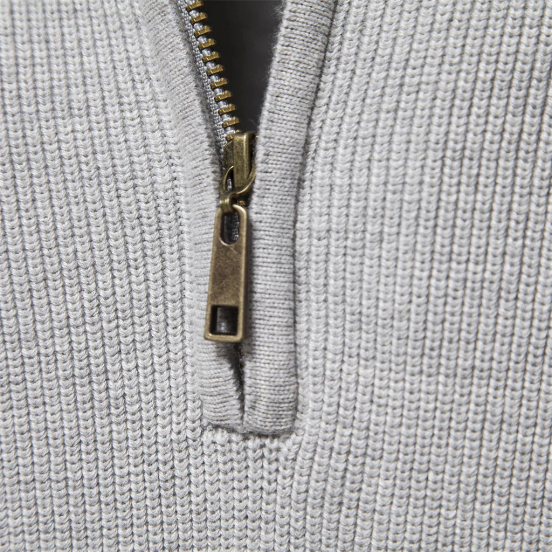 Detail van de half-zip sluiting op een zachte herensweater met stijlvolle ribgebreide mouwen.