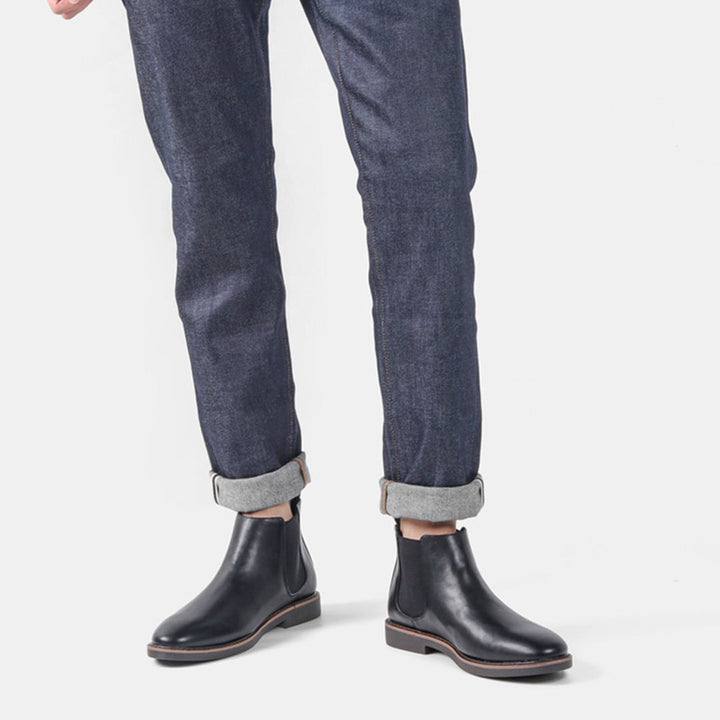 Een man die heren Chelsea laarzen draagt, gecombineerd met een netjes gestylde broek, toont de veelzijdigheid van de schoenen.