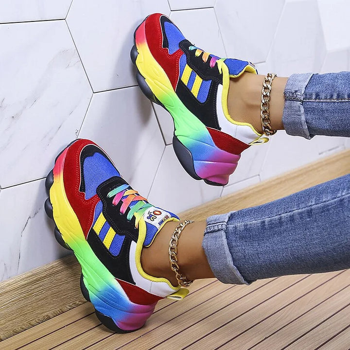 Zijaanzicht van een orthopedische regenboogschoen in het blauw, op een witte achtergrond.