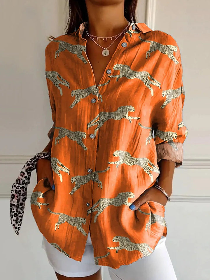 Gedetailleerde weergave van een damesblouse met bloemenprint, lange mouwen en klassieke kraag, toont de stof en het patroon.