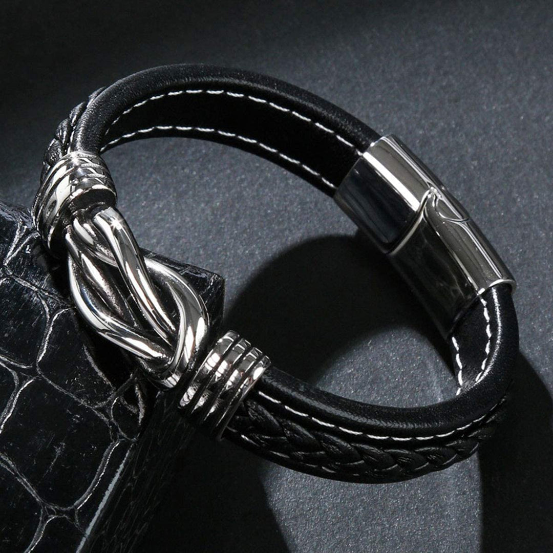 Dames infinity armband met gevlochten lederen band en elegante knoop, afgewerkt met een robuuste magnetische sluiting.