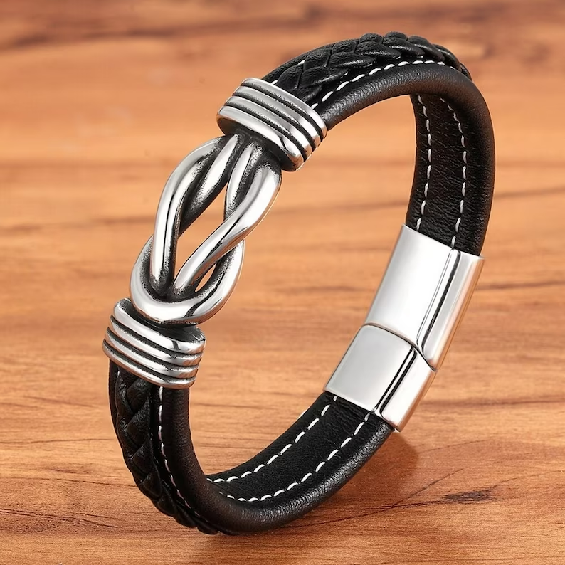 Close-up van zwarte lederen damesarmband met infinity knoop detail en glanzende magnetische sluiting, robuust.