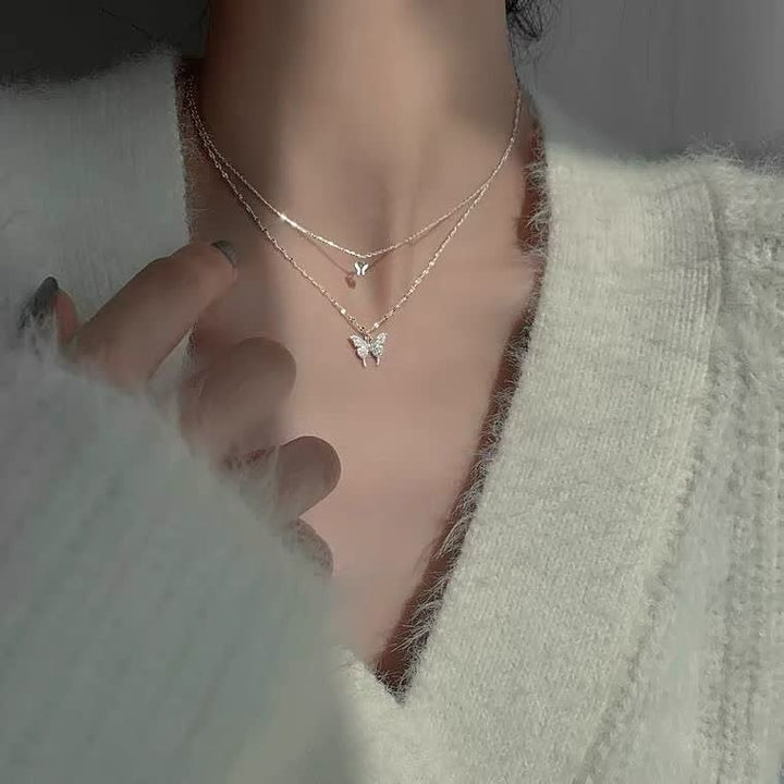 Damesketting met zilveren vlinderhanger om de hals van een model, trendy sieraad.