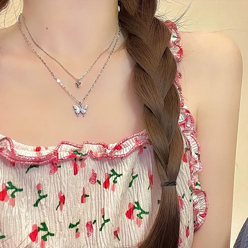 Zilveren vlinderketting voor dames, liggend gepresenteerd als elegant accessoire.