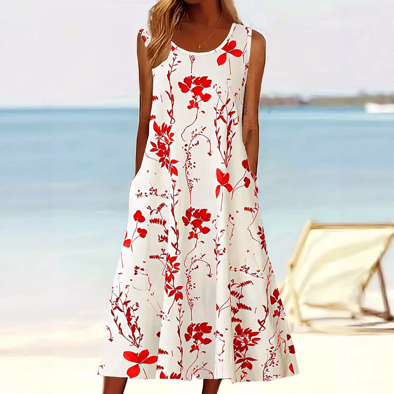 Vrouw op het strand in een witte A-lijn jurk met rood bloemendesign, comfortabel en stijlvol.