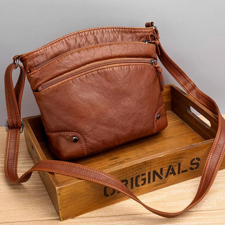 Elegante dames schoudertas van bruin leer, robuust en stijlvol, met verstelbare banden en magnetische sluiting.