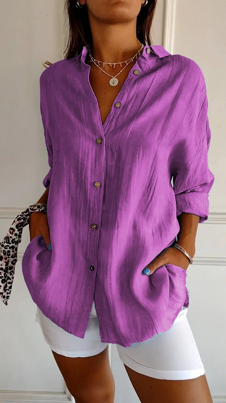 Elegante damesblouse Naya in crème, nauwsluitend en van fijn materiaal voor feestelijke gelegenheden, op een grijze achtergrond.