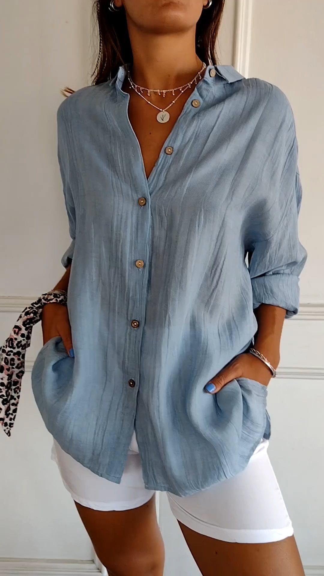 Elegante damesblouse Naya in crème, nauwsluitend en van fijn materiaal voor feestelijke gelegenheden, op een grijze achtergrond.