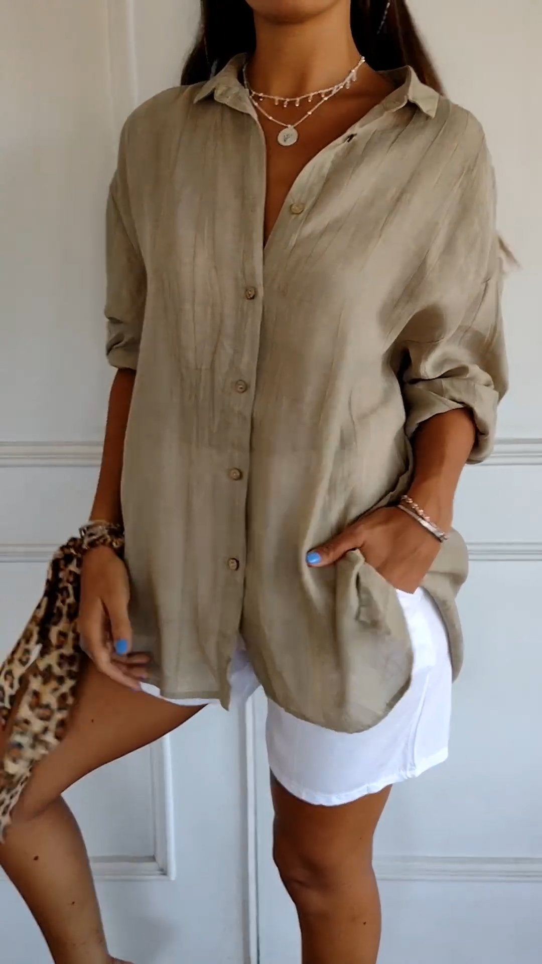 Elegante damesblouse Naya in crème, nauwsluitend en van fijn materiaal voor feestelijke gelegenheden, op een grijze achtergrond.
