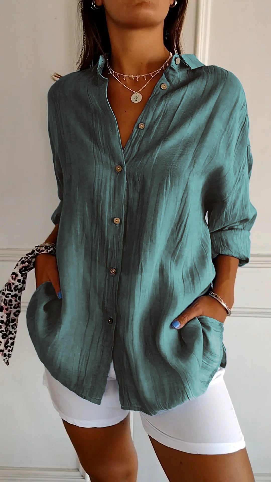 Elegante damesblouse Naya in crème, nauwsluitend en van fijn materiaal voor feestelijke gelegenheden, op een grijze achtergrond.