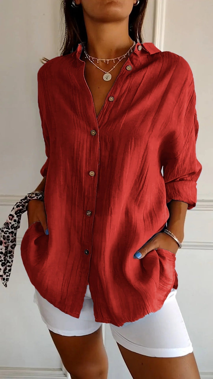 Elegante damesblouse Naya in crème, nauwsluitend en van fijn materiaal voor feestelijke gelegenheden, op een grijze achtergrond.
