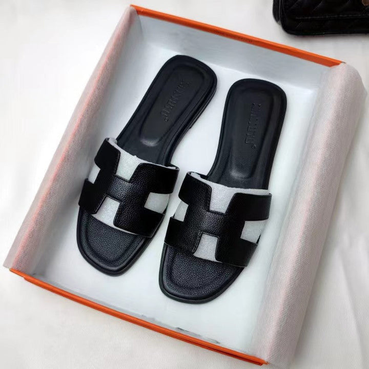 Damesmodel draagt de Hermes geïnspireerde bruine sandalen.