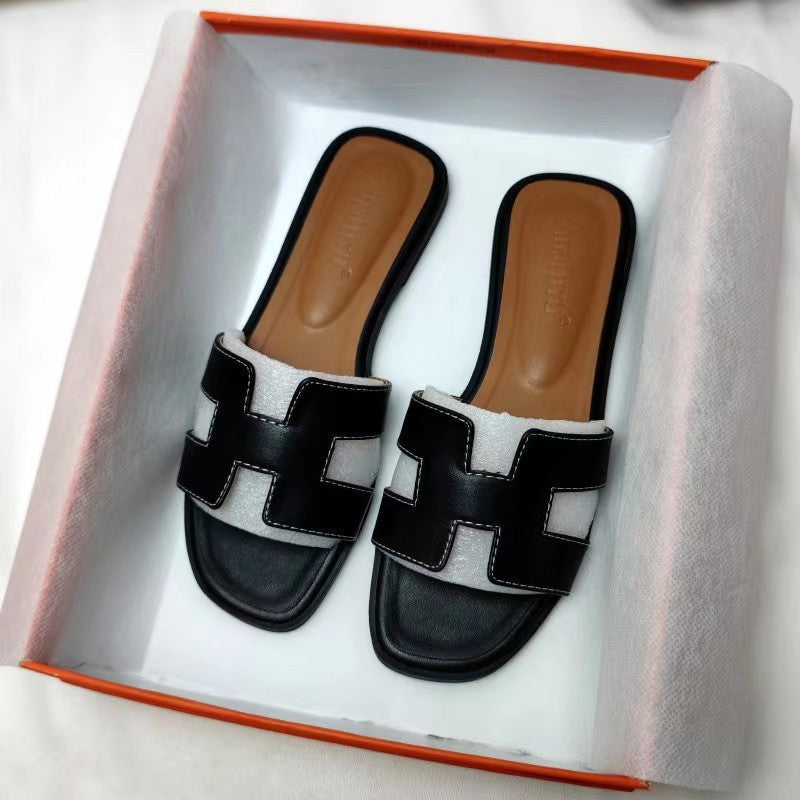 Damesmodel draagt de Hermes geïnspireerde zwarte sandalen.