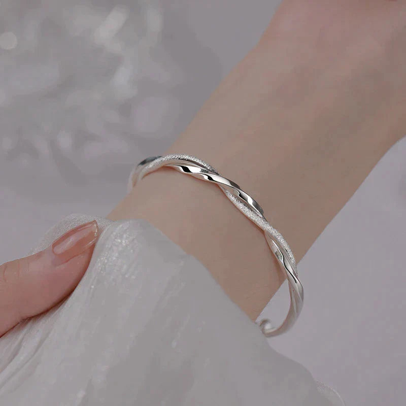 Elegante gedraaide damesarmband, zilverkleurig en verstelbaar. Perfect als stijlvol sieraad en accessoire.