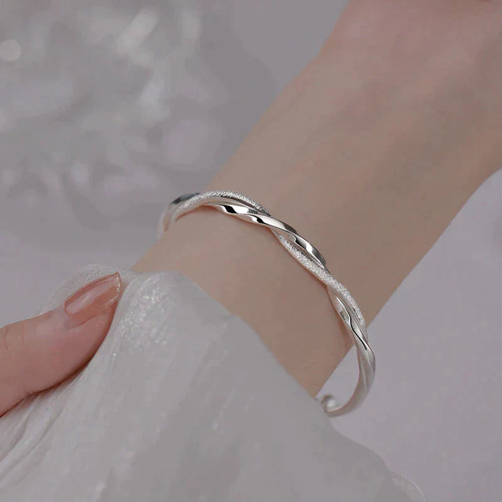 Elegante gedraaide damesarmband, zilverkleurig en verstelbaar. Perfect als stijlvol sieraad en accessoire.