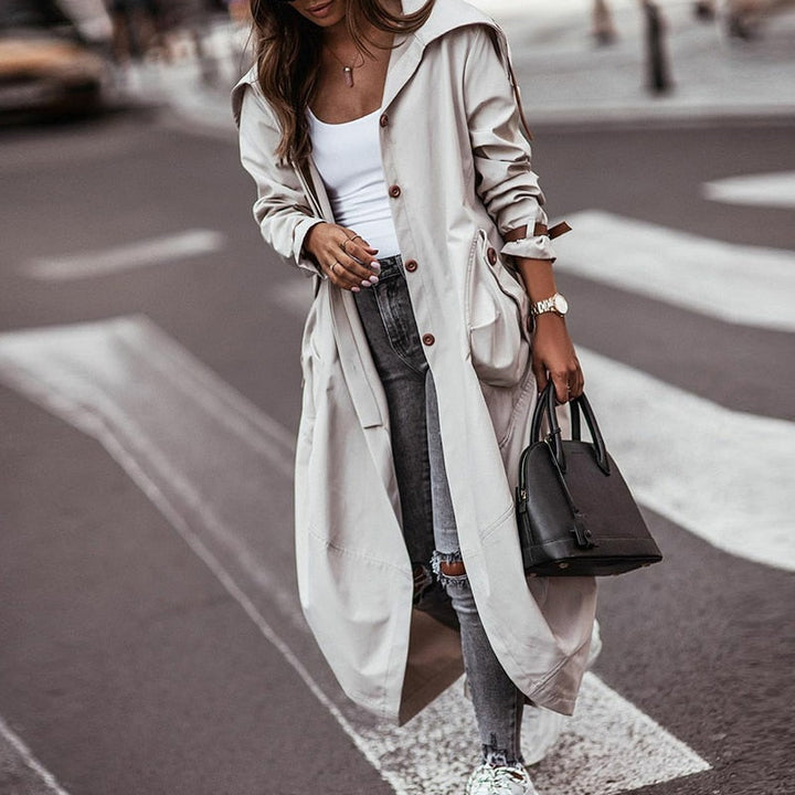 Elegante grijze dames trenchcoat. Lange stijlvolle jas met zakken, perfect voor lente en herfst bovenkleding.