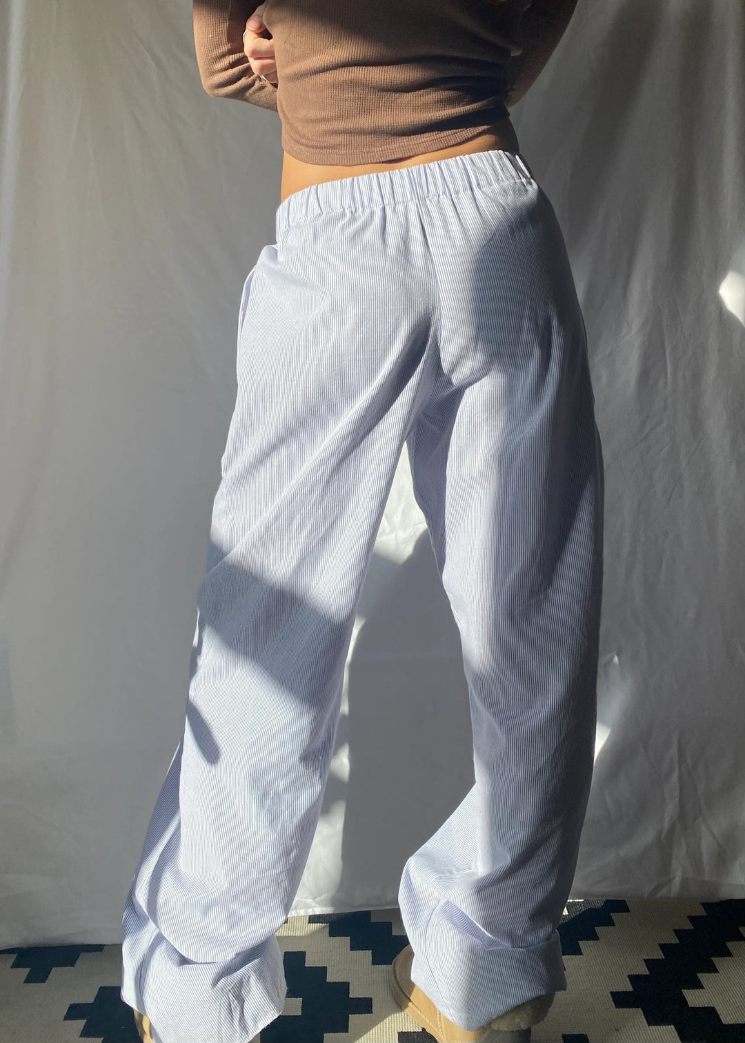 Close-up van de elastische tailleband van de gestreepte loungebroek in verschillende kleuren.