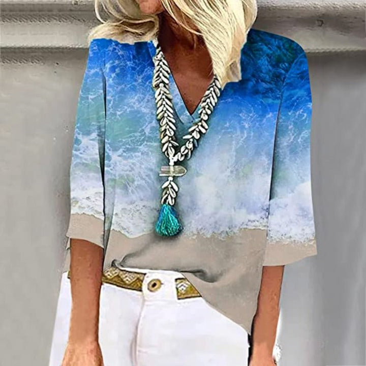 Detail van de elegante, luchtige damesblouse met kristalblauwe nuances en zandtinten.