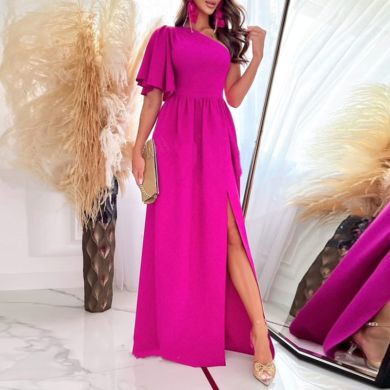 Damesmode: Lange avondjurk met one-shoulder en sensuele split, voor een glamoureuze look.