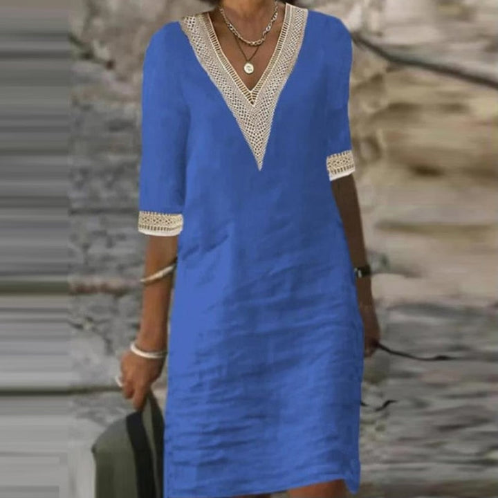 Model draagt de elegante witte linnen zomerjurk voor dames in een buitenomgeving.