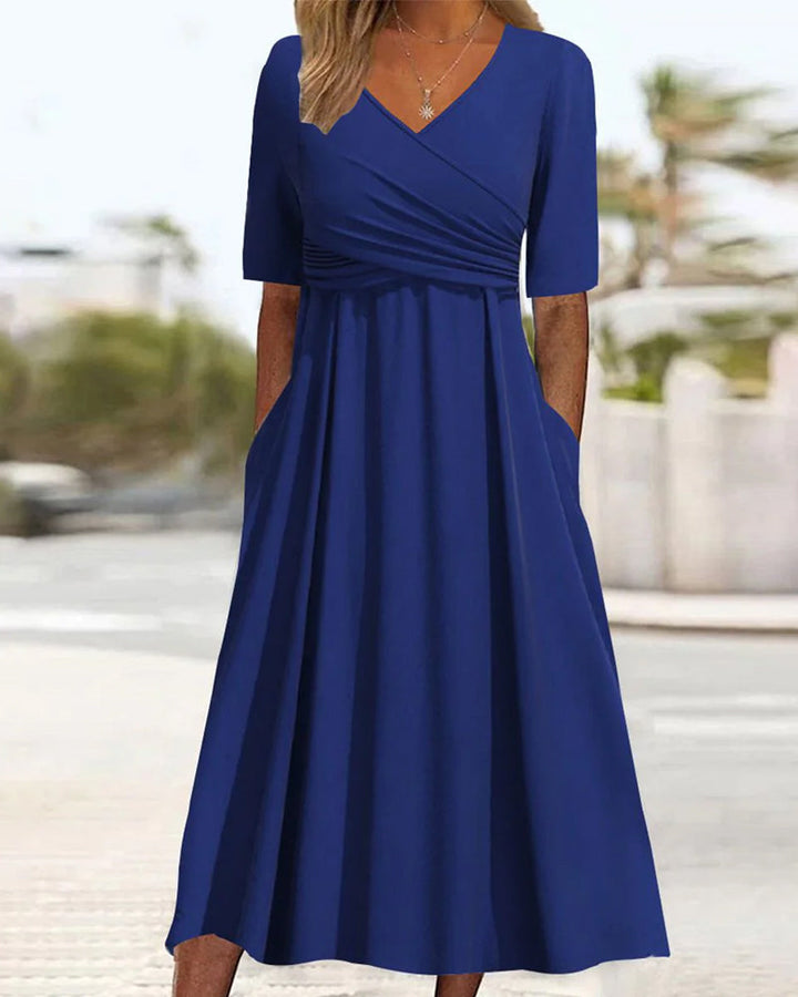 Een vrouw toont een elegante blauwe omslagmidi-jurk, ideaal voor zowel formele als casual gelegenheden.