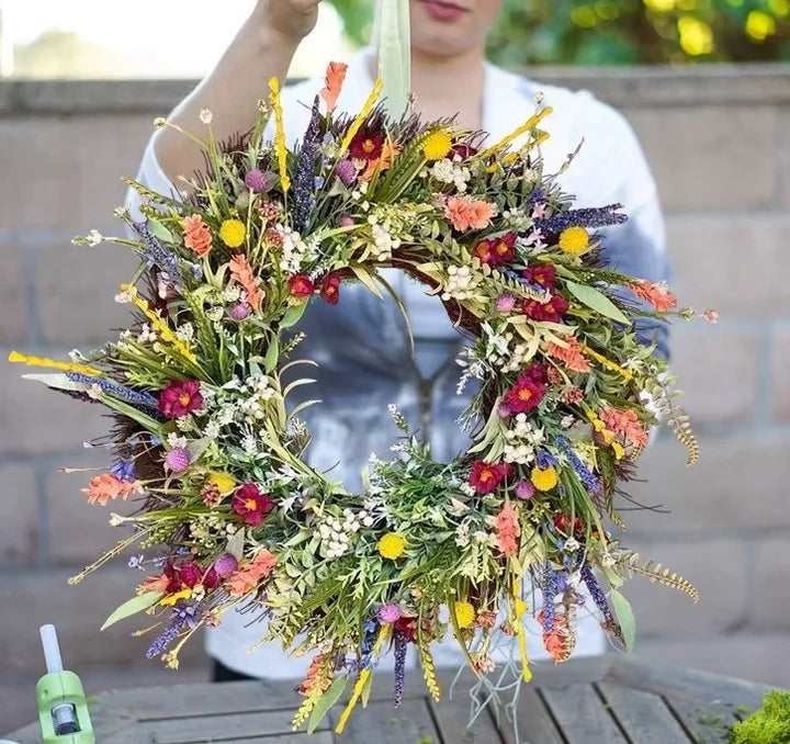 Handgemaakte krans van kunstwilde bloemen met rustiek ontwerp, blauwe lupinen en Indian paintbrush op natuurlijke achtergrond