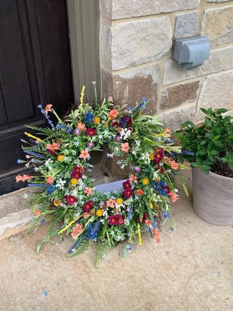 Handgemaakte krans van kunstwilde bloemen met rustiek ontwerp, blauwe lupinen en Indian paintbrush op natuurlijke achtergrond