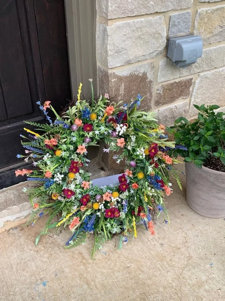 Handgemaakte krans van kunstwilde bloemen met rustiek ontwerp, blauwe lupinen en Indian paintbrush op natuurlijke achtergrond