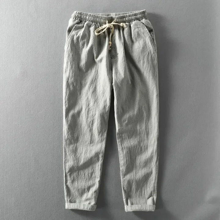 Man zittend op een bankje, draagt een beige zomerbroek, toont hoe veelzijdig de broek is voor dagelijks gebruik.