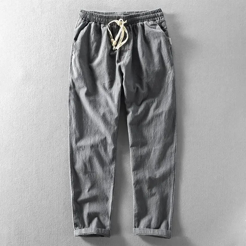 Man die de tailleband van de beige zomerbroek verstelt, toont het draagcomfort en de verstelbaarheid.
