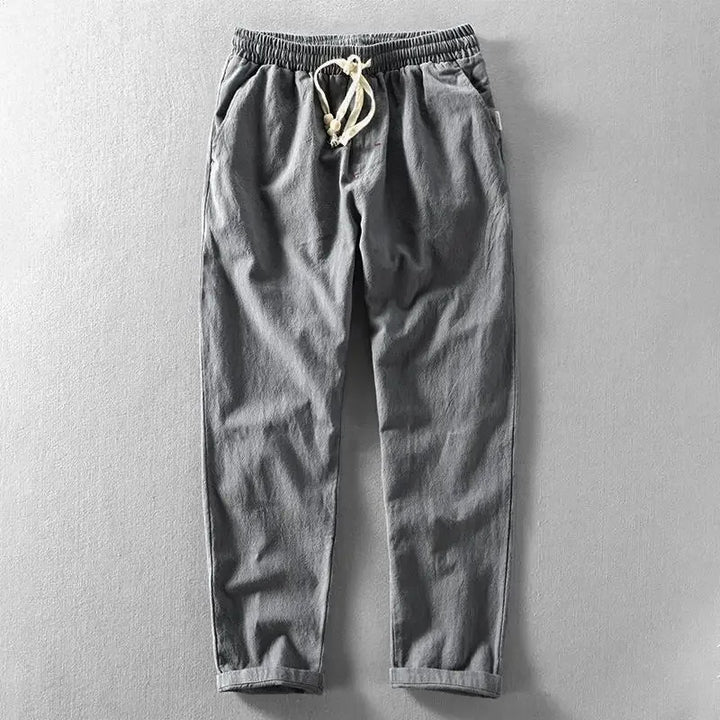 Man die de tailleband van de beige zomerbroek verstelt, toont het draagcomfort en de verstelbaarheid.