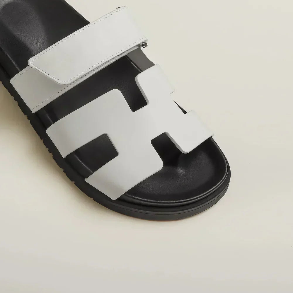 Zwarte Klara Chypre Sandalen op een houten ondergrond.