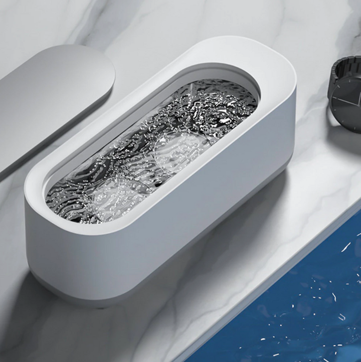 Compacte witte ultrasoonreiniger, ideaal voor 360° reiniging van sieraden en brillen; efficiënte technologie voor thuis.