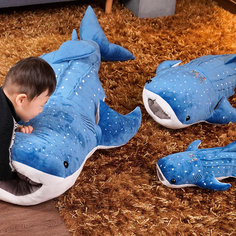 Kinderen knuffelend met de grote blauwe walvishaai knuffel op een bank, illustreert comfort en plezier.
