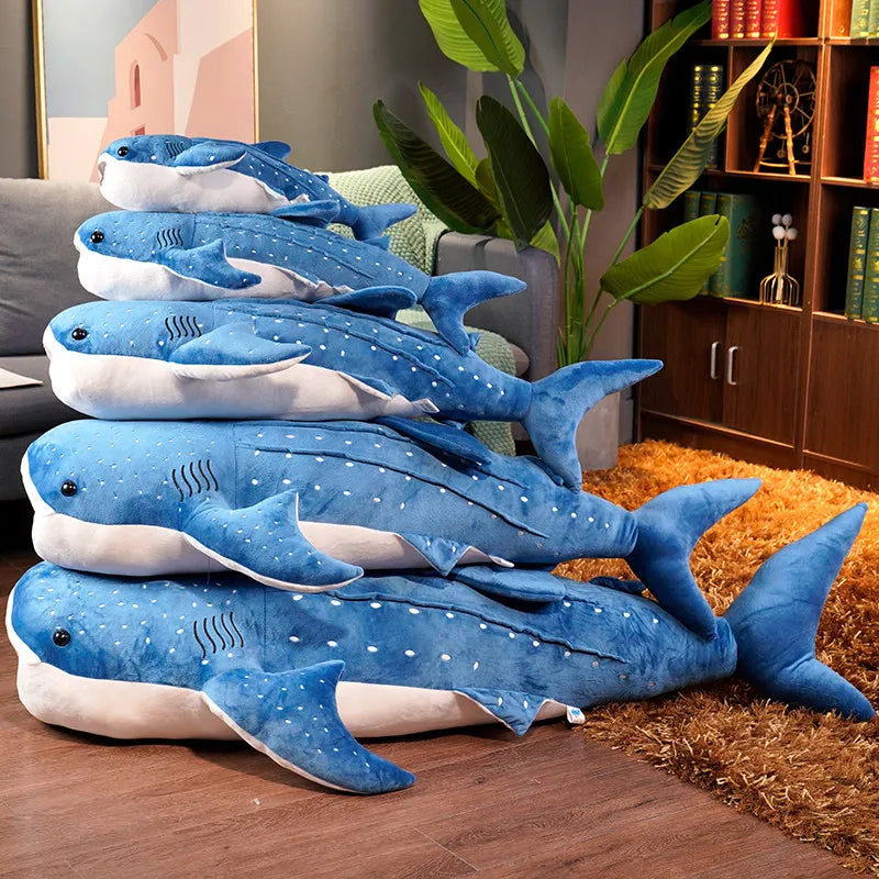 De blauwe walvishaai knuffel liggend op een bed, toont de royale afmetingen en de zachte textuur.