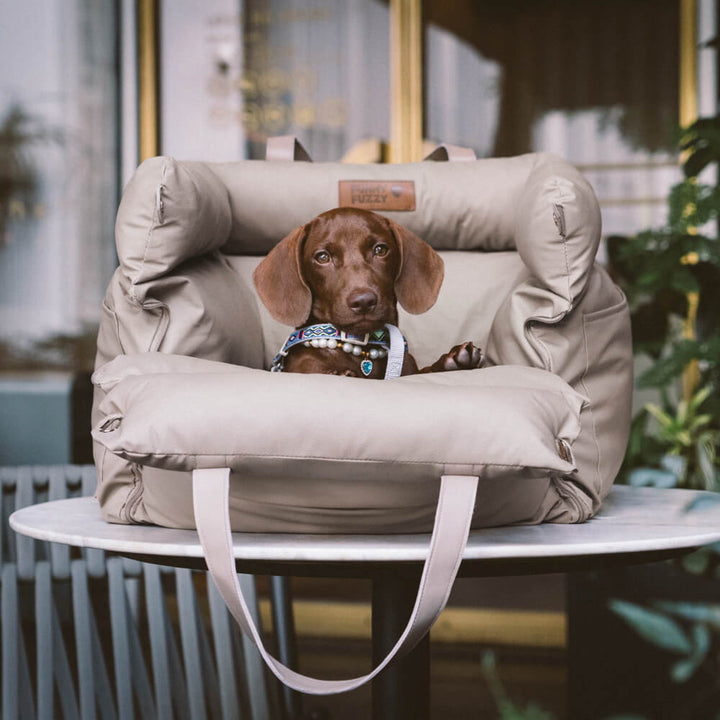 Luxe hondenautostoel van kunstleer, beige, met zachte bekleding en veiligheidsgordel voor comfortabel reizen.