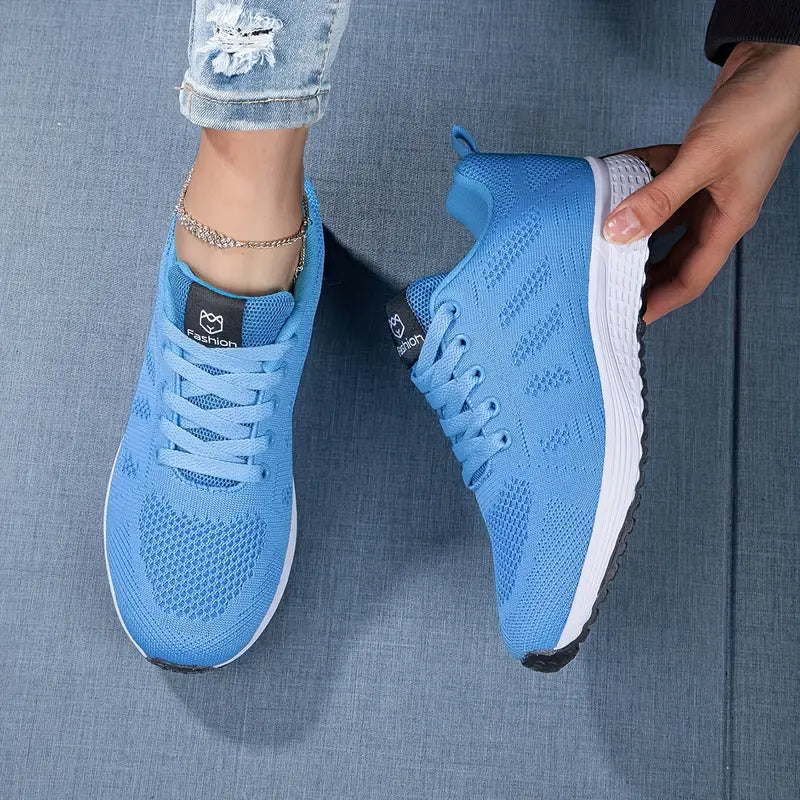 Moderne ademende dames sneaker in witgrijs, van de zijkant gezien met vetersluiting, ideaal voor vrije tijd en sport.