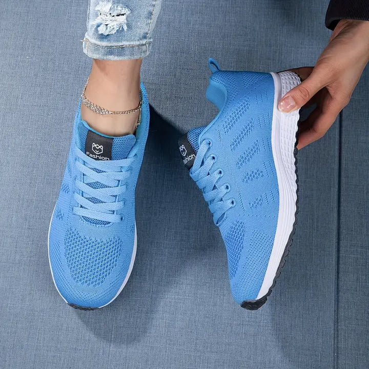 Moderne ademende dames sneaker in witgrijs, van de zijkant gezien met vetersluiting, ideaal voor vrije tijd en sport.