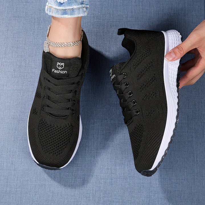Moderne ademende dames sneaker in witgrijs, van de zijkant gezien met vetersluiting, ideaal voor vrije tijd en sport.