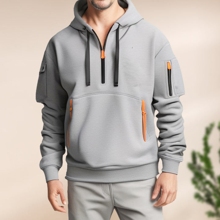 Man wandelt casual in de grijze Adriano Hoodie, wat het draagcomfort benadrukt.