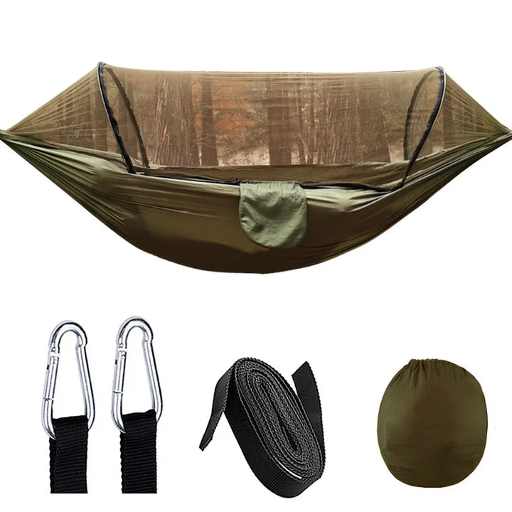 Outdoor hangmat met muskietennet, gemaakt van groene parachutestof, hangend tussen twee bomen, ideaal voor kamperen.