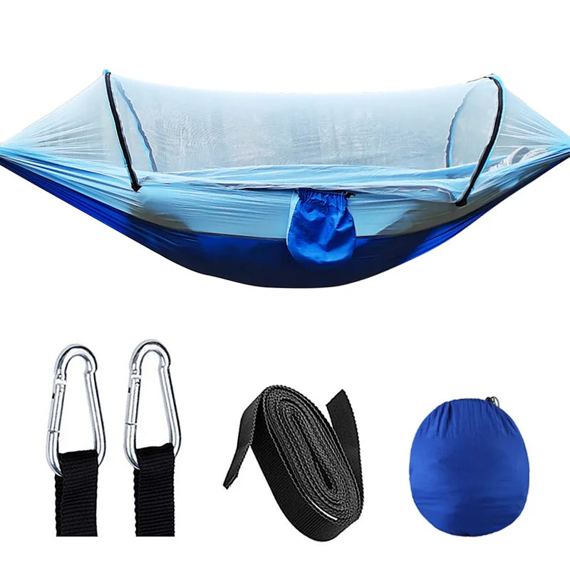 Outdoor hangmat met muskietennet, gemaakt van groene parachutestof, hangend tussen twee bomen, ideaal voor kamperen.