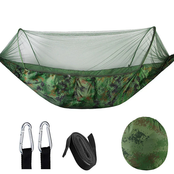 Outdoor hangmat met muskietennet, gemaakt van groene parachutestof, hangend tussen twee bomen, ideaal voor kamperen.