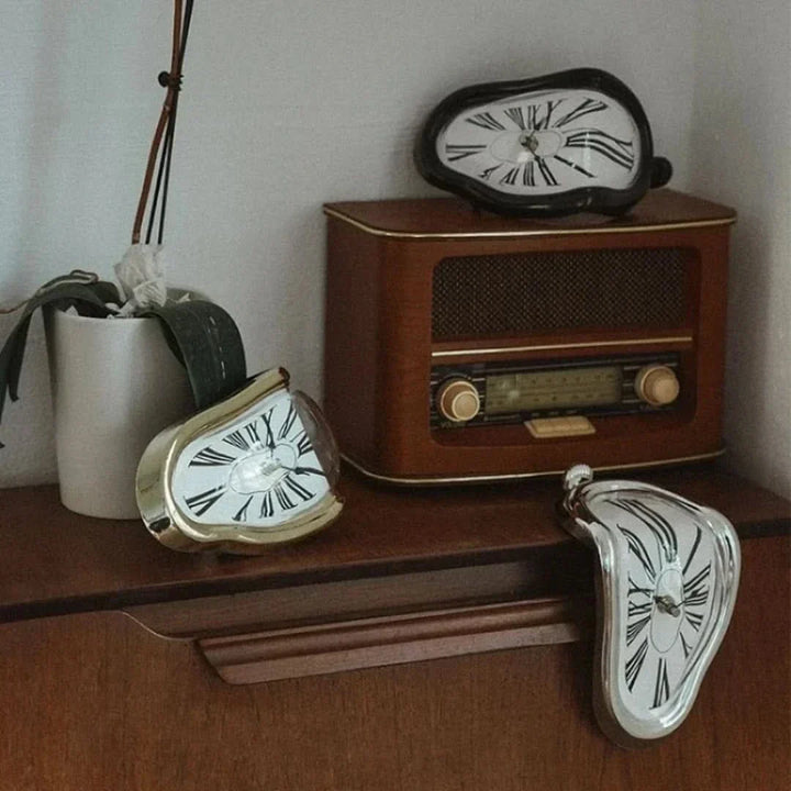 Smeltende decoratieve klok, surrealistisch Salvador Dalí design, gouden en zwarte klok op een plank