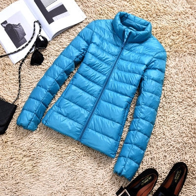 Ultraleichte blaue Damenjacke, wasserabweisend, Stil frontansicht mit verstellbarer Kapuze und praktischen Taschen.