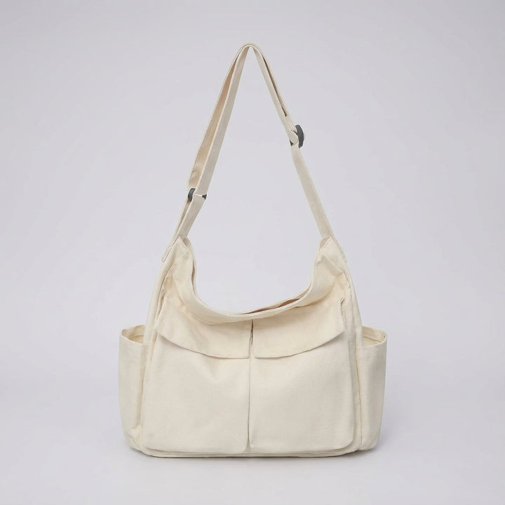 Model draagt een praktische canvas messenger tas als crossbody. Ideaal voor dagelijks unisex gebruik. Ruime schoudertas.