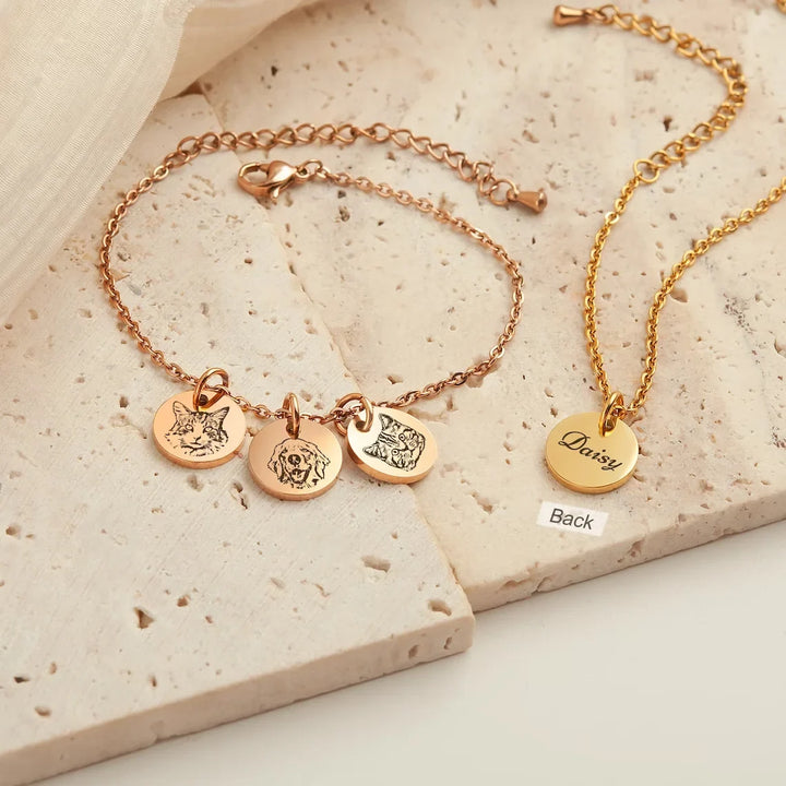 Close-up van een gepersonaliseerde zilveren huisdier armband met gegraveerde naam en pootafdruk, unisex.