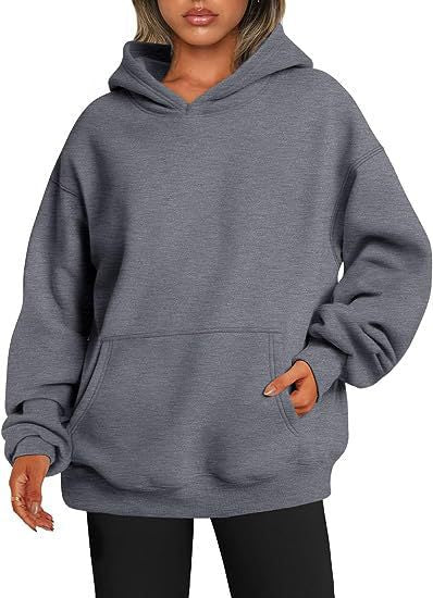 Vrouw draagt een grijze unisex hoodie, relaxte pose.