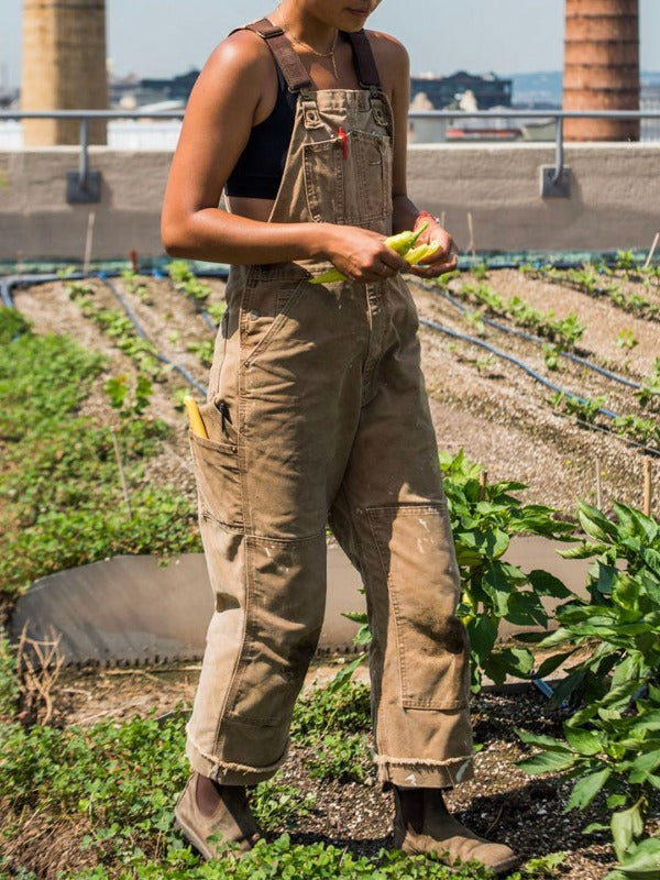 Unisex tuinbroek, groen, met schouderbanden en zakken, robuust en comfortabel voor buitenwerk en flexibele bewegingen.