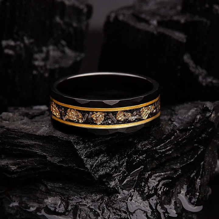 Close-up van wolfram ring met gedetailleerd gouden blad en korrelige zwarte meteoriet inleg.